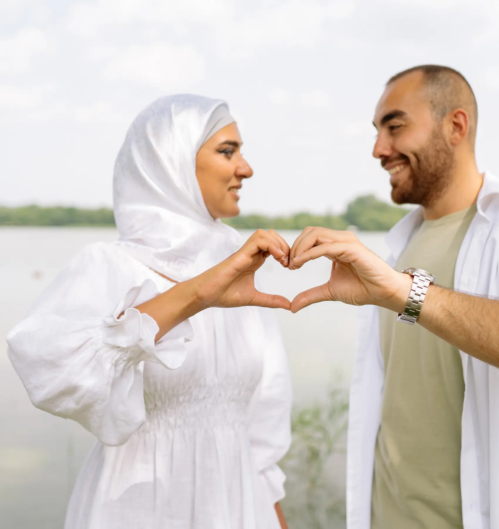 زوجان يشكلان قلبًا بأيديهما أثناء وقوفهما معًا، في رمز للحب والتفاهم وإصلاح العلاقة الزوجية.